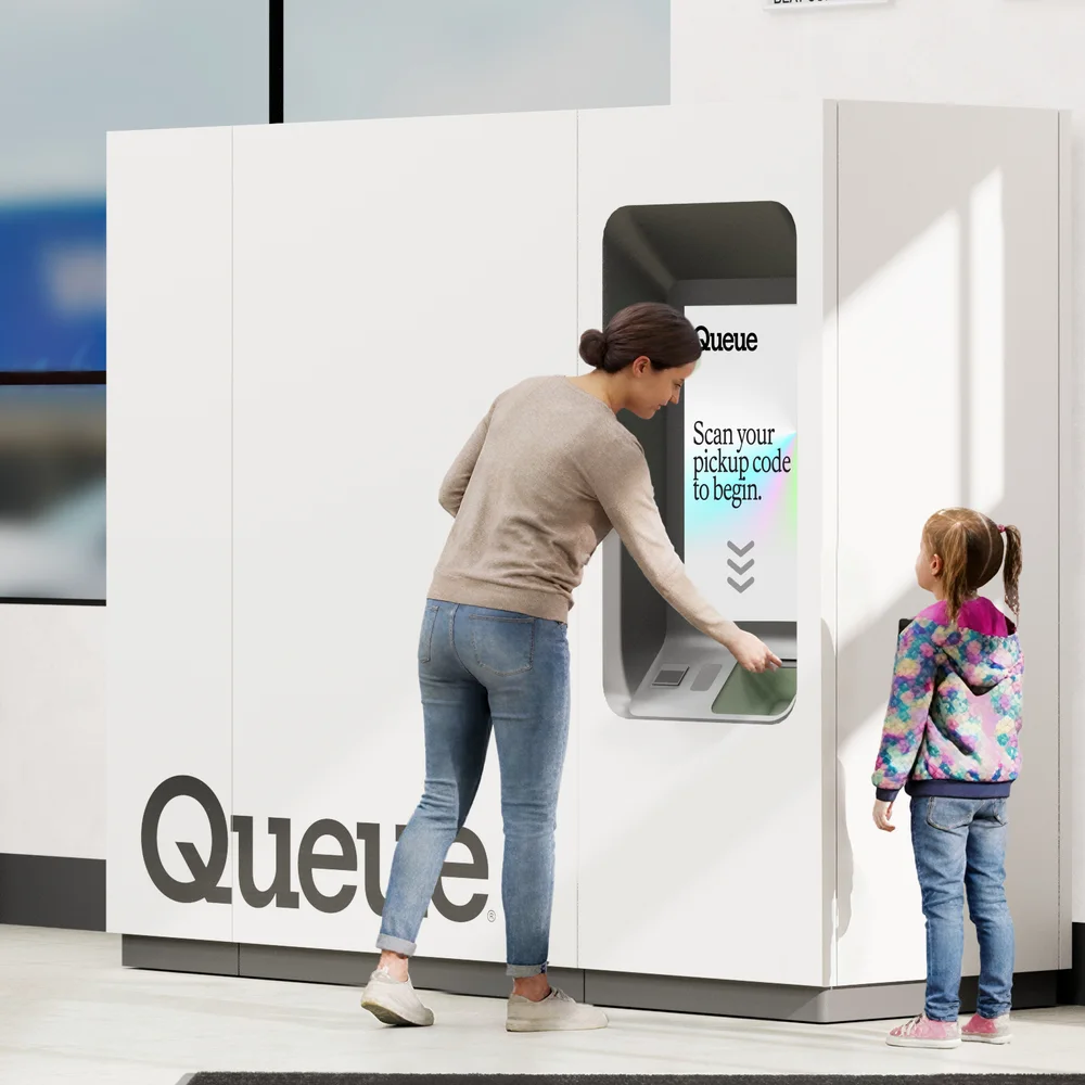A parent and child picking up a prescription at a Queue kiosk inside a store